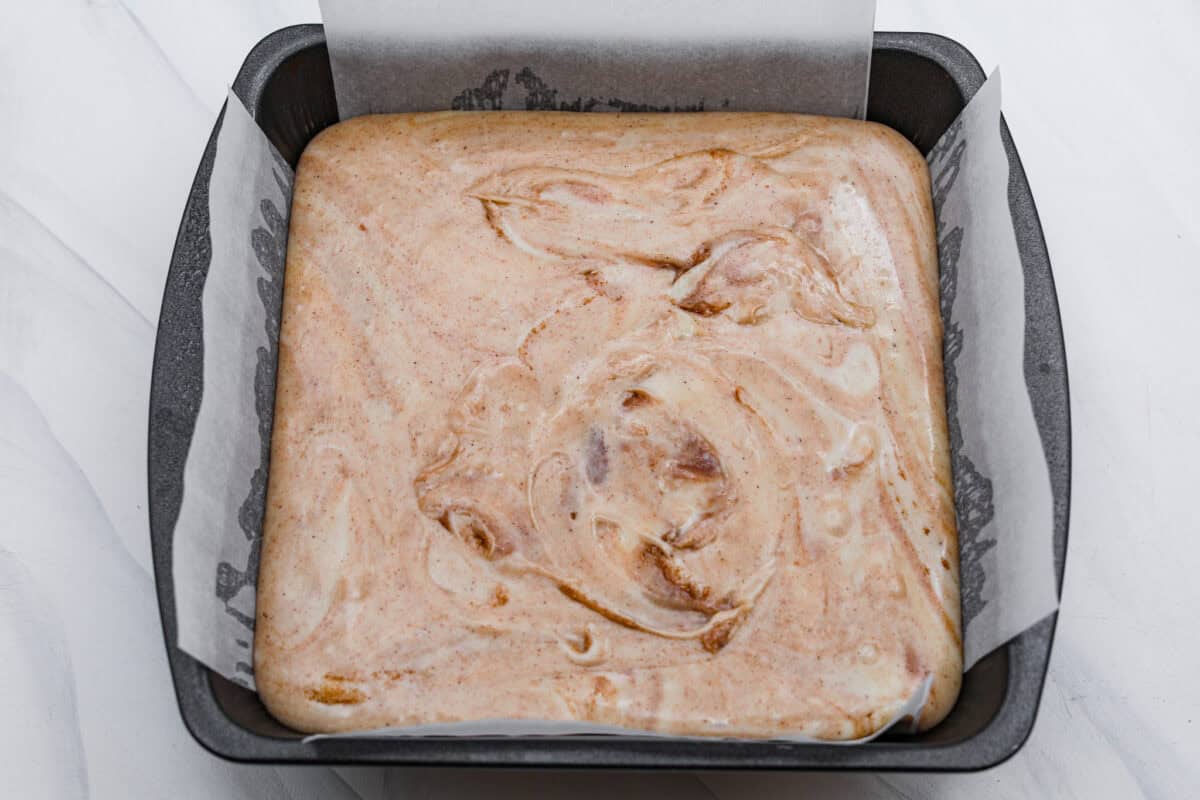 Overhead shot of the fudge mixture poured into a 8x8 pan with parchment paper. 
