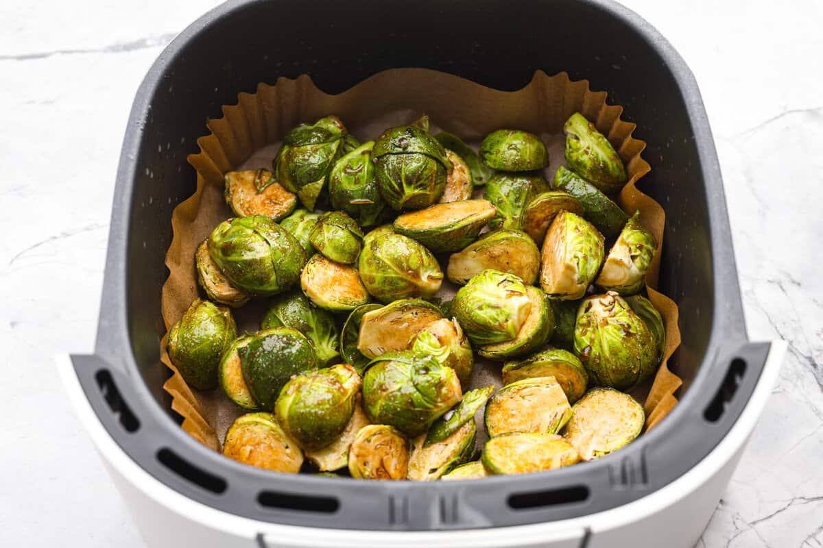 Sauce coated sprouts in the air fryer basket ready to be cooked.