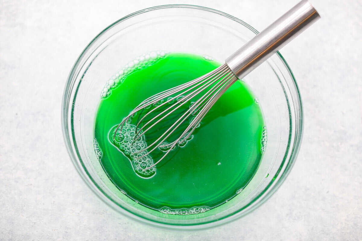 Lime Jello whisked with boiling water in a larg mixing bowl.