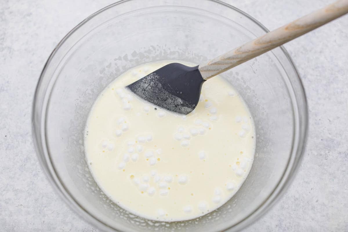 Middle layer of lemon Jello and mini marshmallows mixed and dissolving in boiling water.