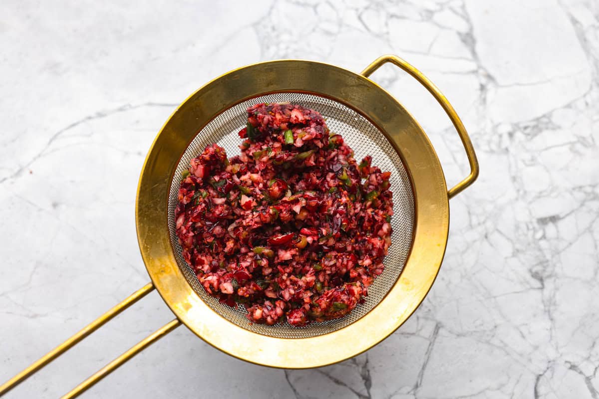 Cranberry mixture in a fine mesh strainer being drained. 