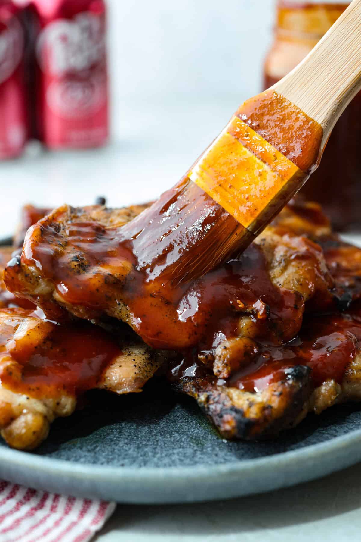 Someone spreading Dr Pepper BBQ sauce on some grilled chicken.