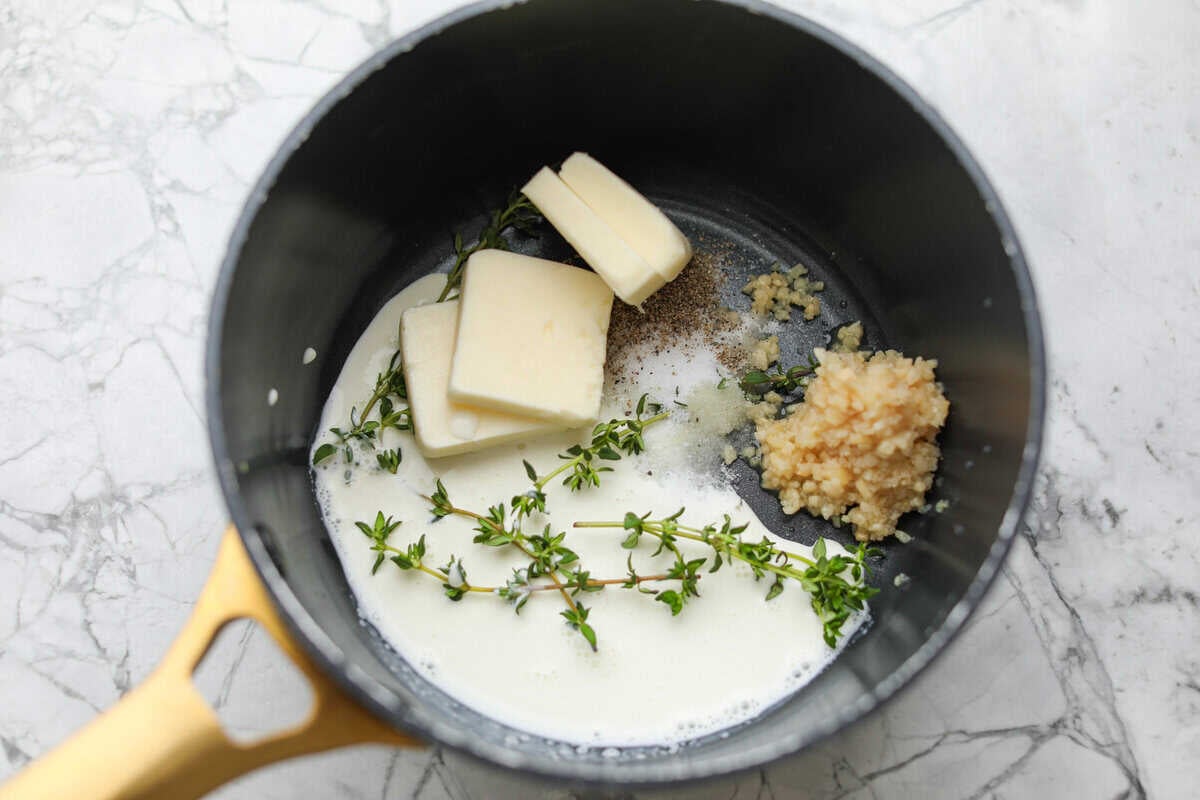 Butter, milk, garlic and herbs in a saucepan.