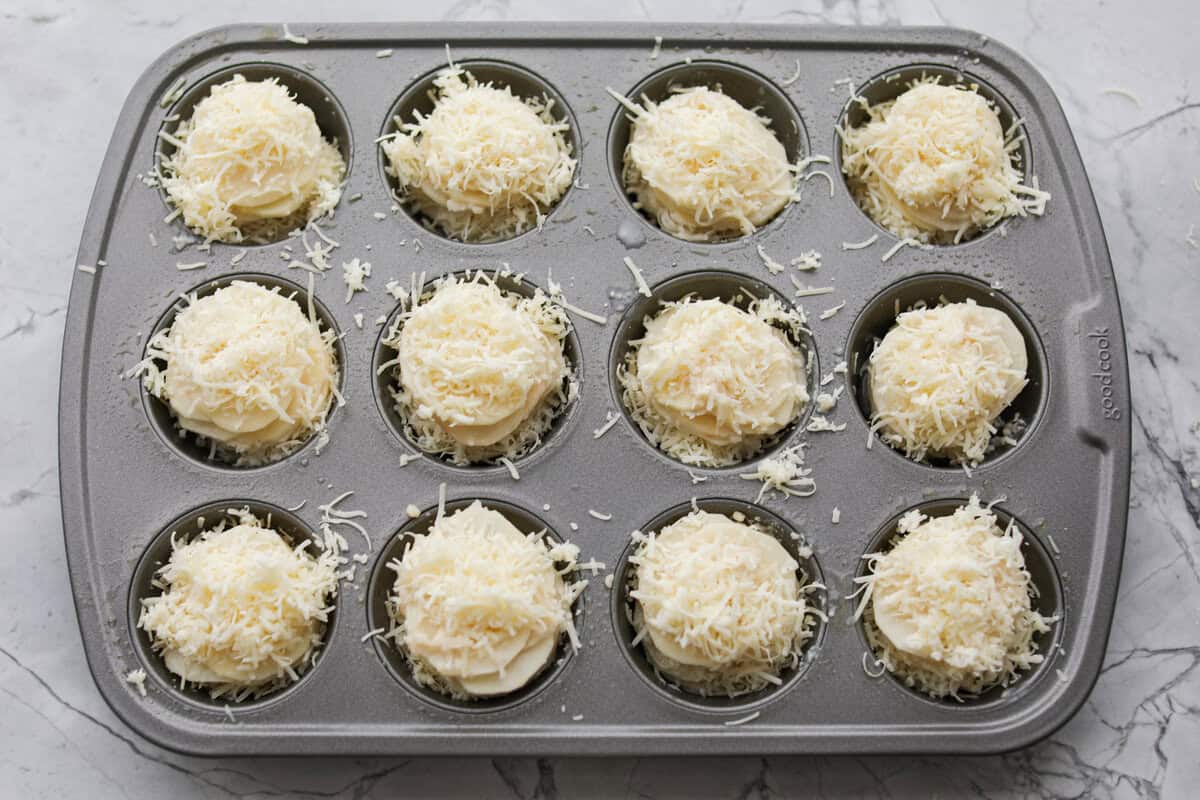 Potato stacks topped with cheese and ready to go in the oven.