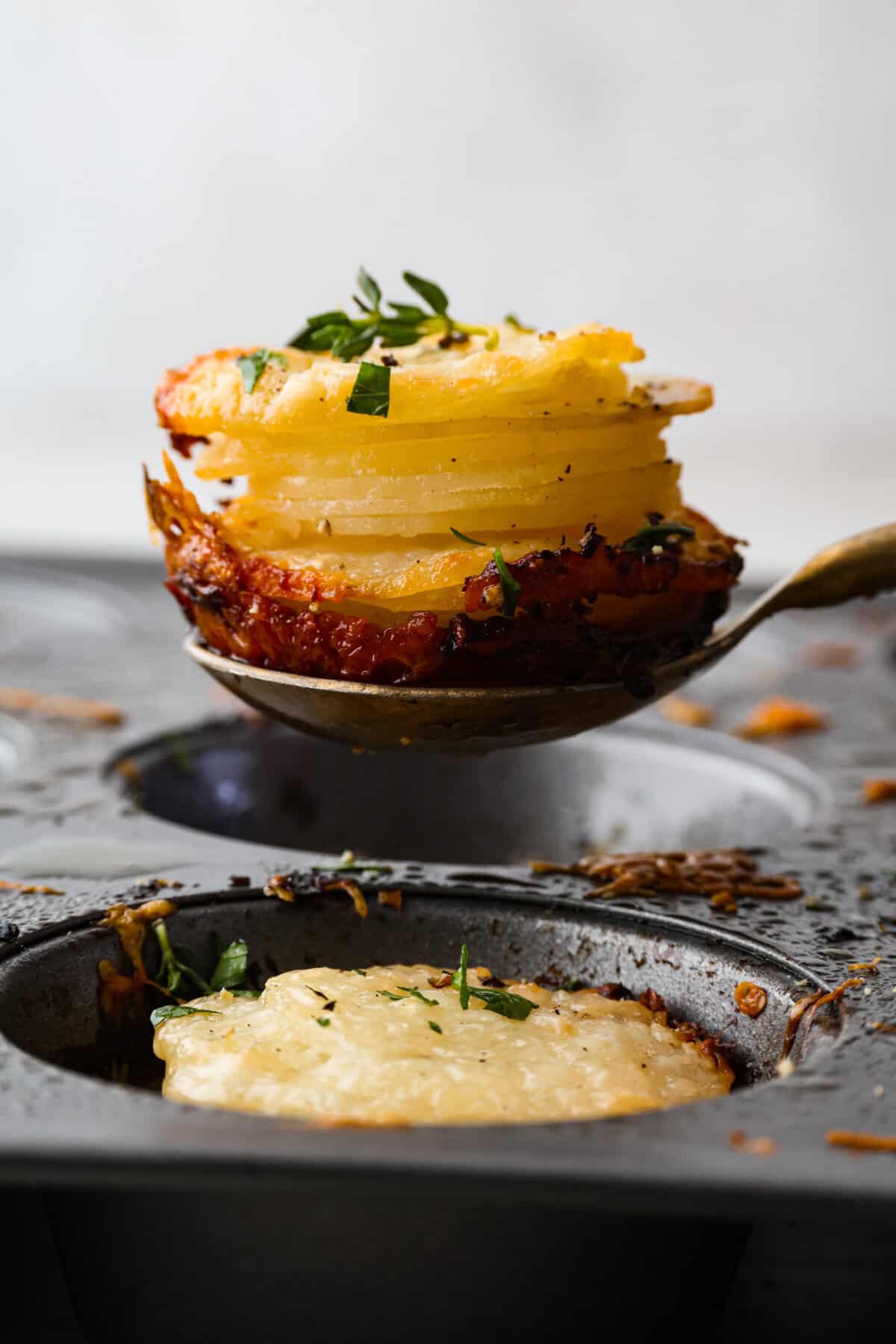 Someone lifting a potato stack out of the muffin tin.