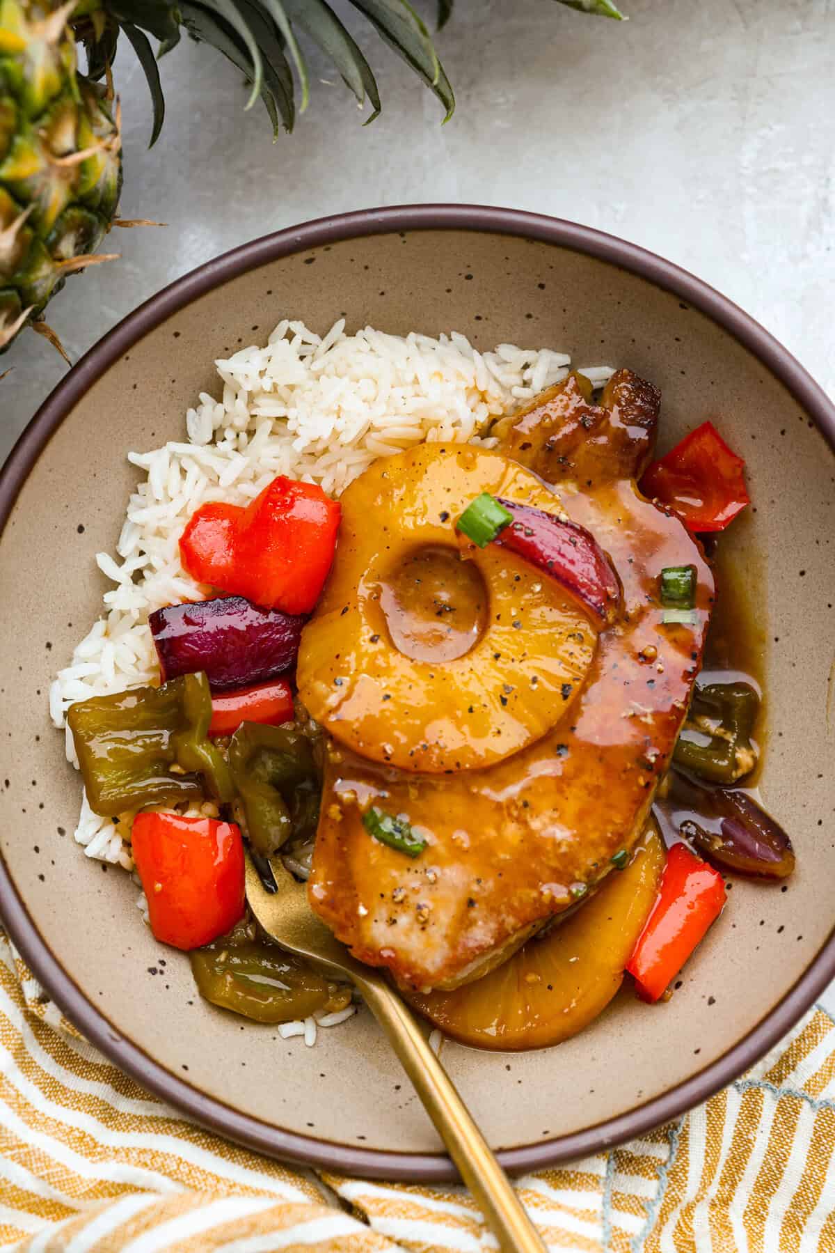 Plated Hawaiian pork chops on a bed of rice.