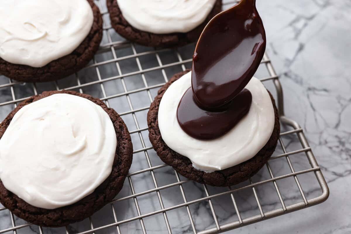 Someone spooning on a dollop of chocolate ganache.