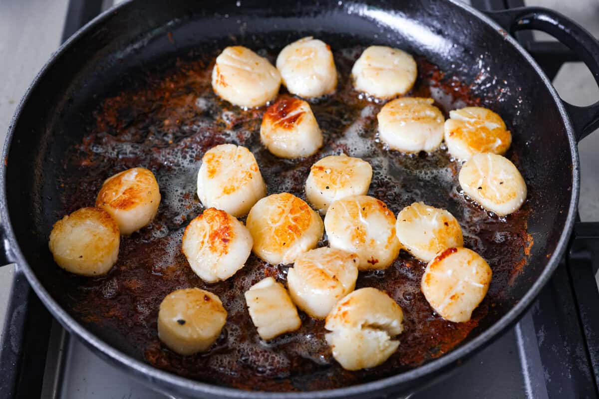 Scallops in a pan searing.