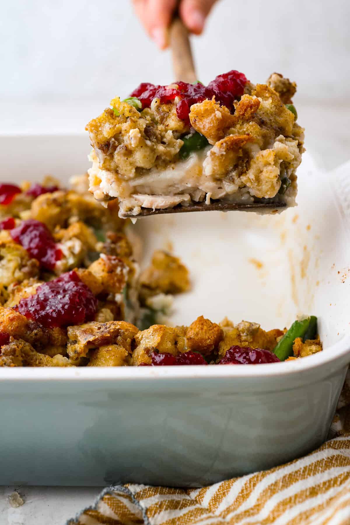Someone lifting a serving of Thanksgiving leftover casserole out of the baking dish.