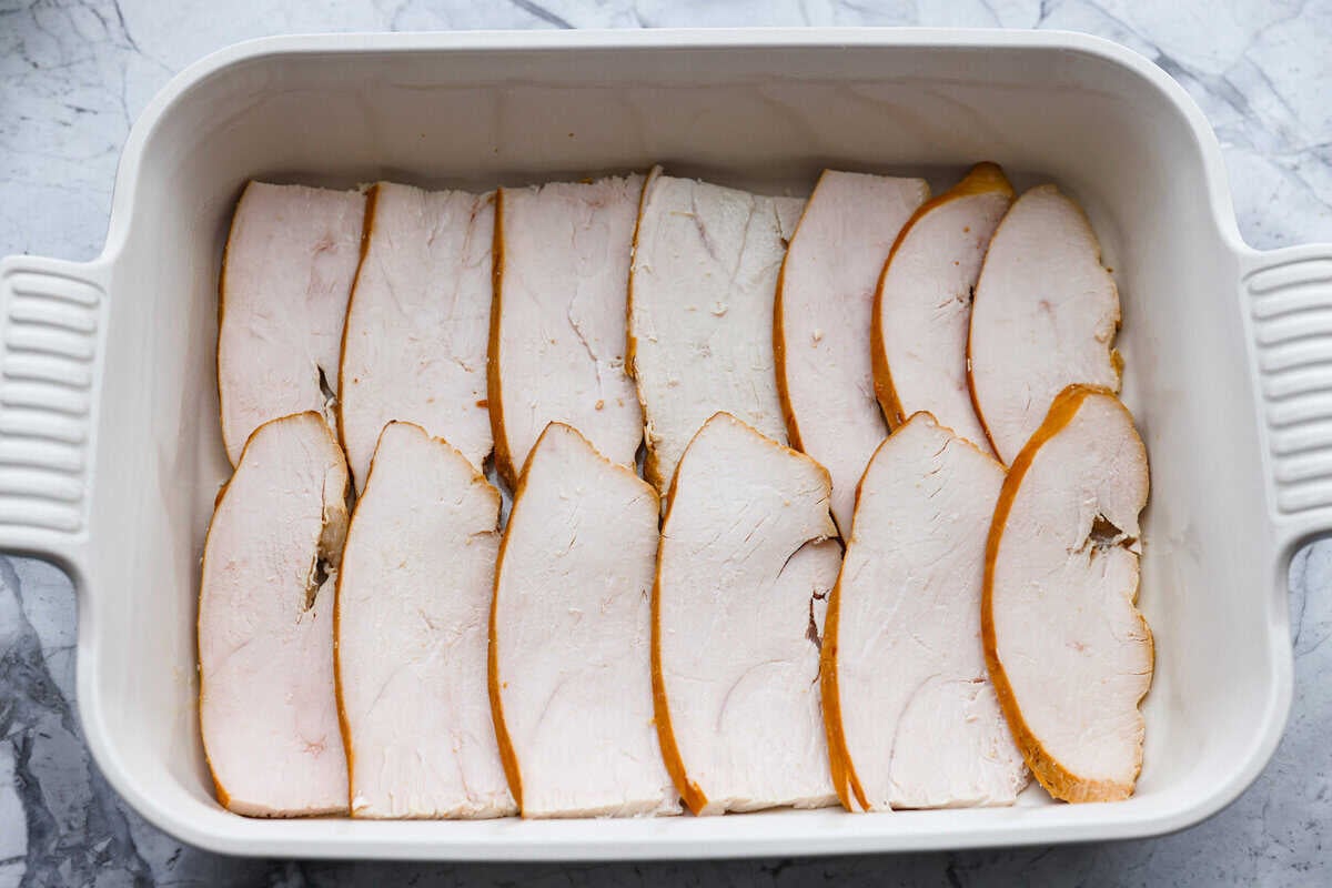 Turkey slices layered on the bottom of a baking dish.