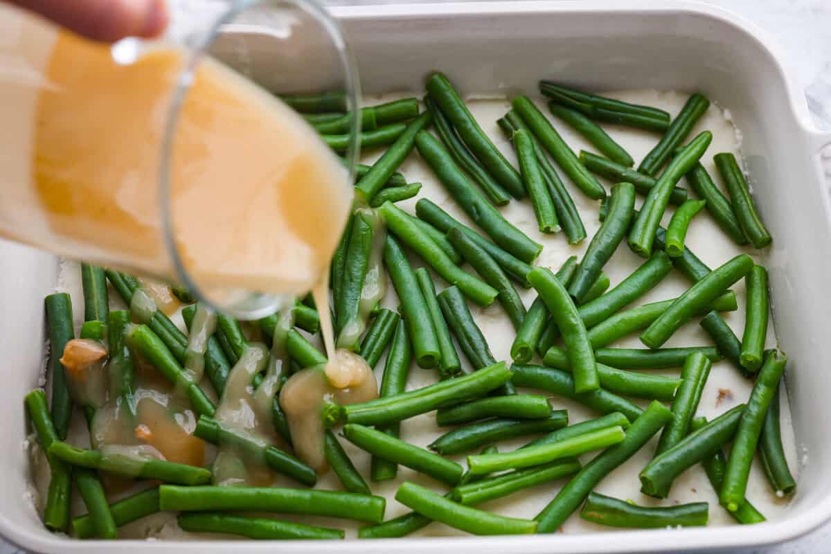 Gravy being poured over the top of the green beans.