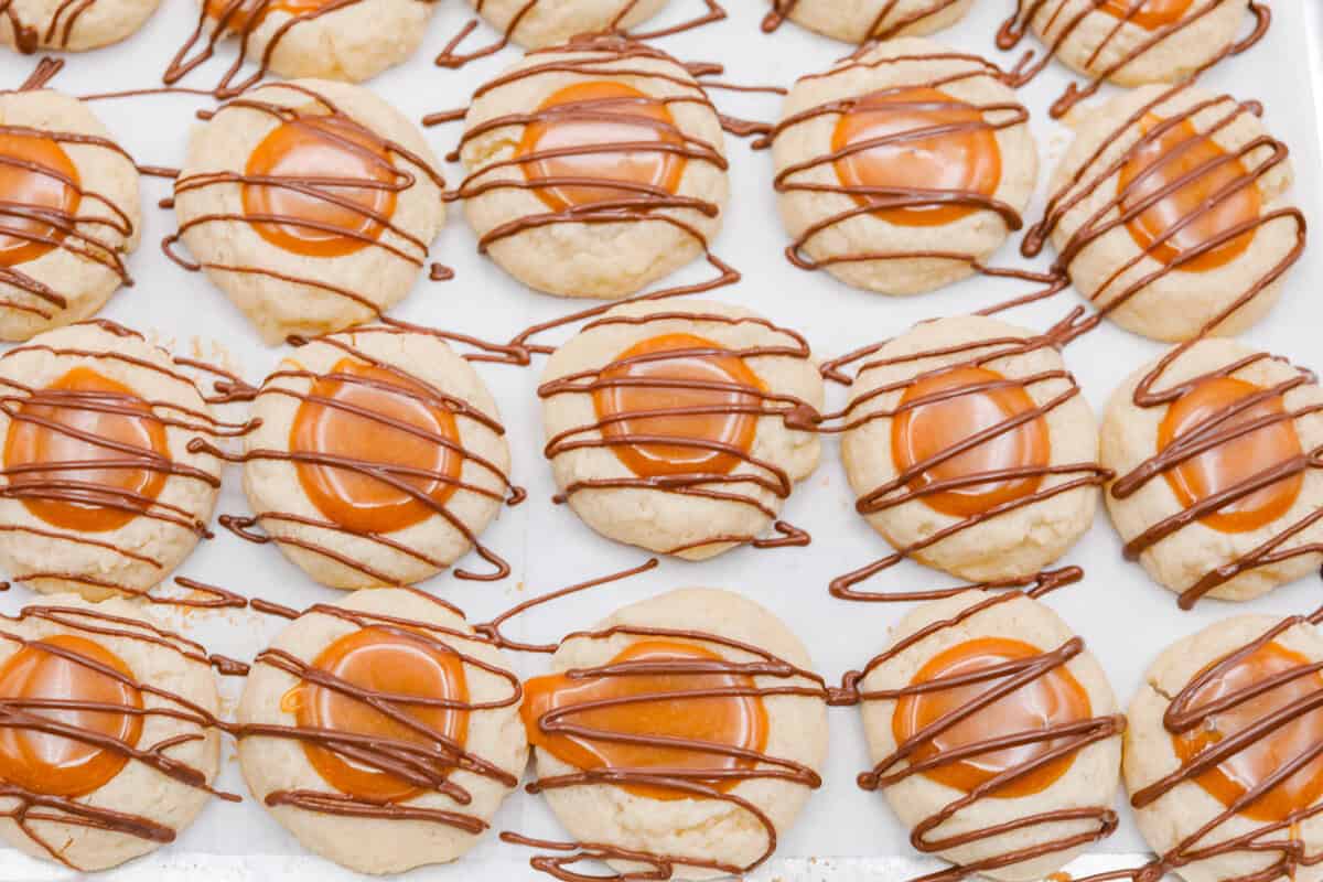 Chocolate drizzled over the top of the Twix thumbprint cookies.