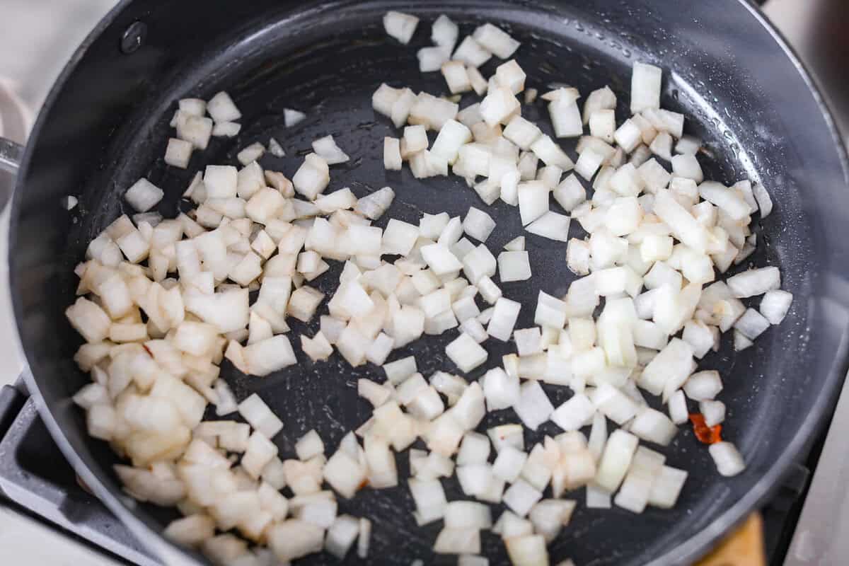 Onions and garlic cooking in a skillet on the stove top.